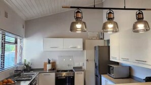 Een moderne keuken met witte kasten, een fornuis, een magnetron en hanglampen.