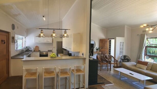 Een moderne keuken met witte kasten, een centraal eiland met barkrukken en hanglampen.