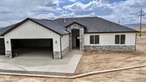 A single-story house with a garage, a stone foundation, and a sloped roof. - The Lyman House (Lyman)