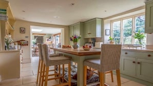 A kitchen with a central island, wooden chairs, and light green cabinets. - 'Darling Buds of May' Glorious 17th Century Idyll (Heddington)