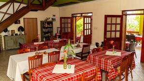 A dining area with red and white checkered tablecloths, wooden chairs, and a staircase. - Roxy's Mountain Lodge (Laudat)