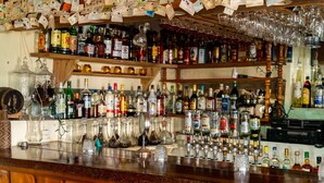A bar with shelves stocked with various liquor bottles and glasses. - Roxy's Mountain Lodge (Laudat)