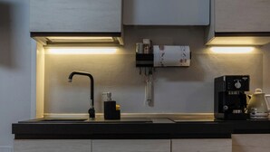 Une cuisine moderne équipée d’un évier encastré, d’une machine à café et d’une bouilloire posées sur le plan de travail.