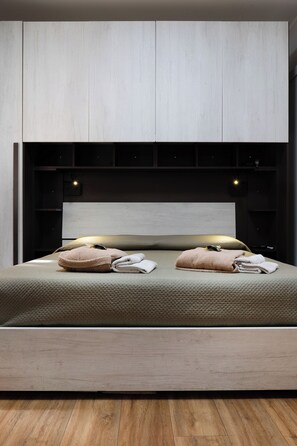 A modern bedroom with a minimalist design, featuring a bed with a textured mattress, two pillows, and a headboard with integrated lighting. - il Loto (Bologna)