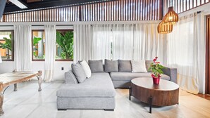 Ein modernes Wohnzimmer mit einer Eckcouch, einem runden Couchtisch und einer Holzbalkendecke.