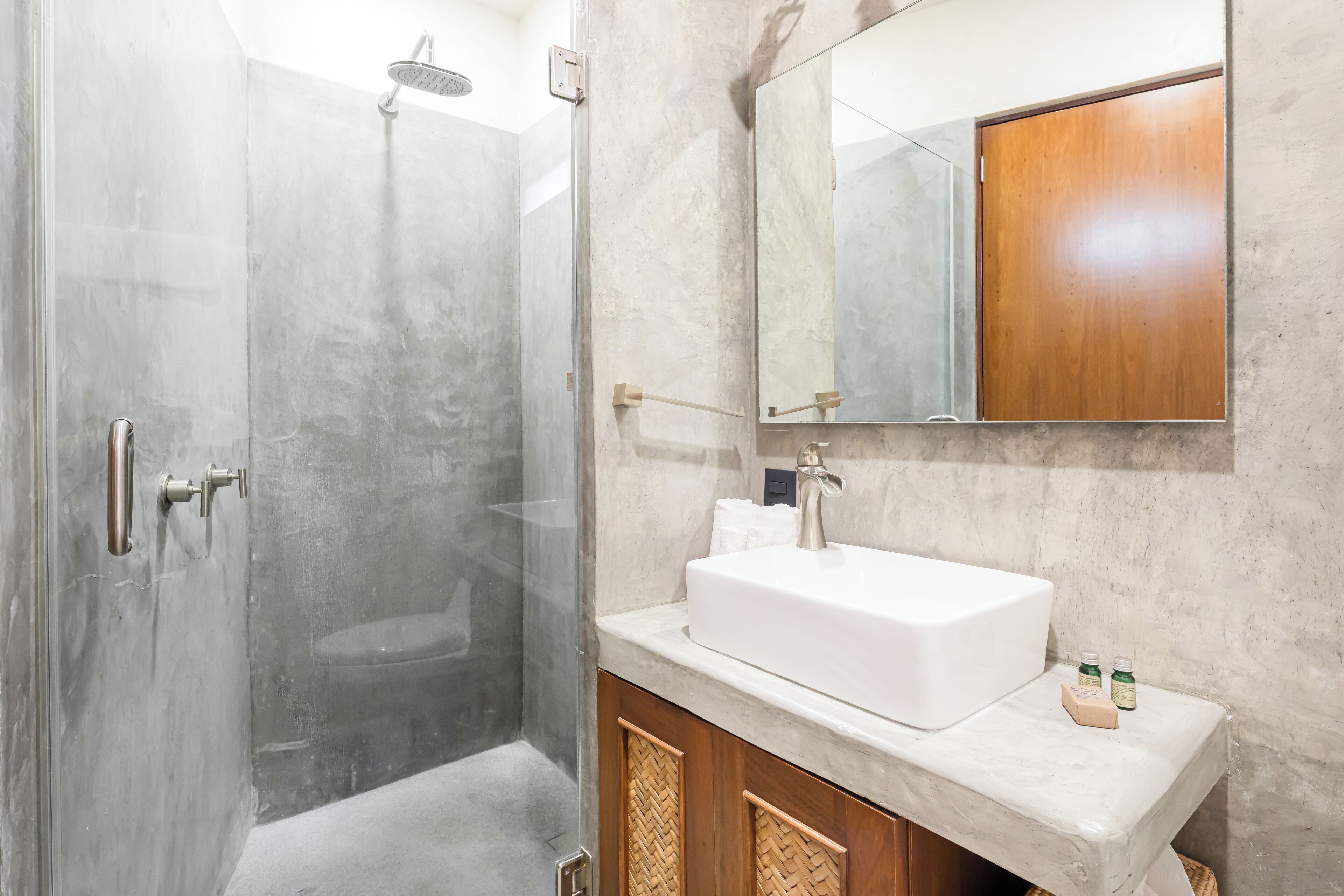 Une salle de bain moderne avec une douche à parois de verre, un lavabo blanc et un meuble en bois.