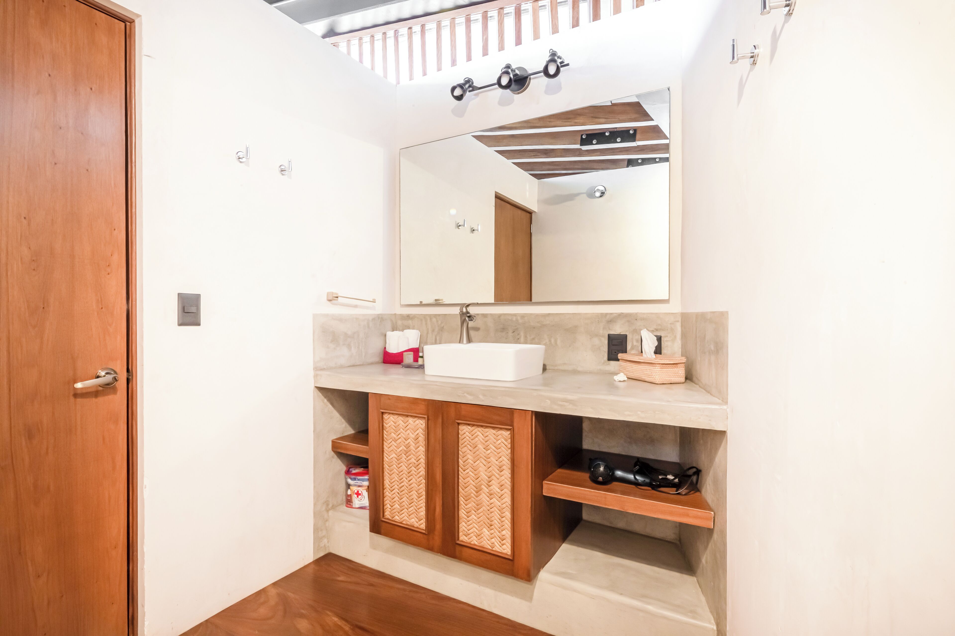 Une salle de bain avec une porte en bois, un lavabo blanc, un miroir et un espace douche.
