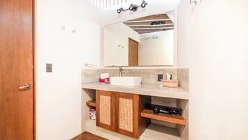 Une salle de bain avec une porte en bois, un lavabo blanc, un miroir et un espace douche.
