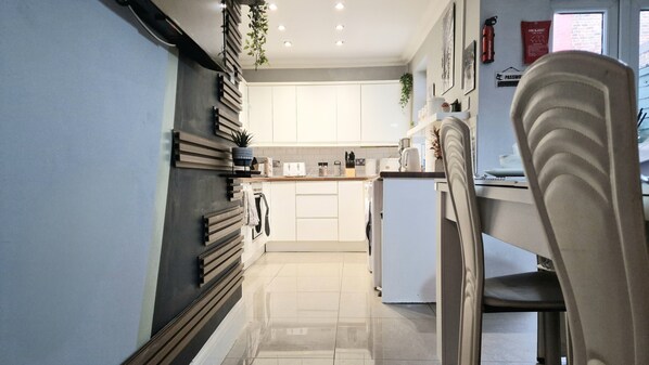 A modern kitchen with white cabinets, a built-in oven, and a countertop with various appliances. - Stunning 5-bed House in Liverpool! Great Location! (Liverpool)