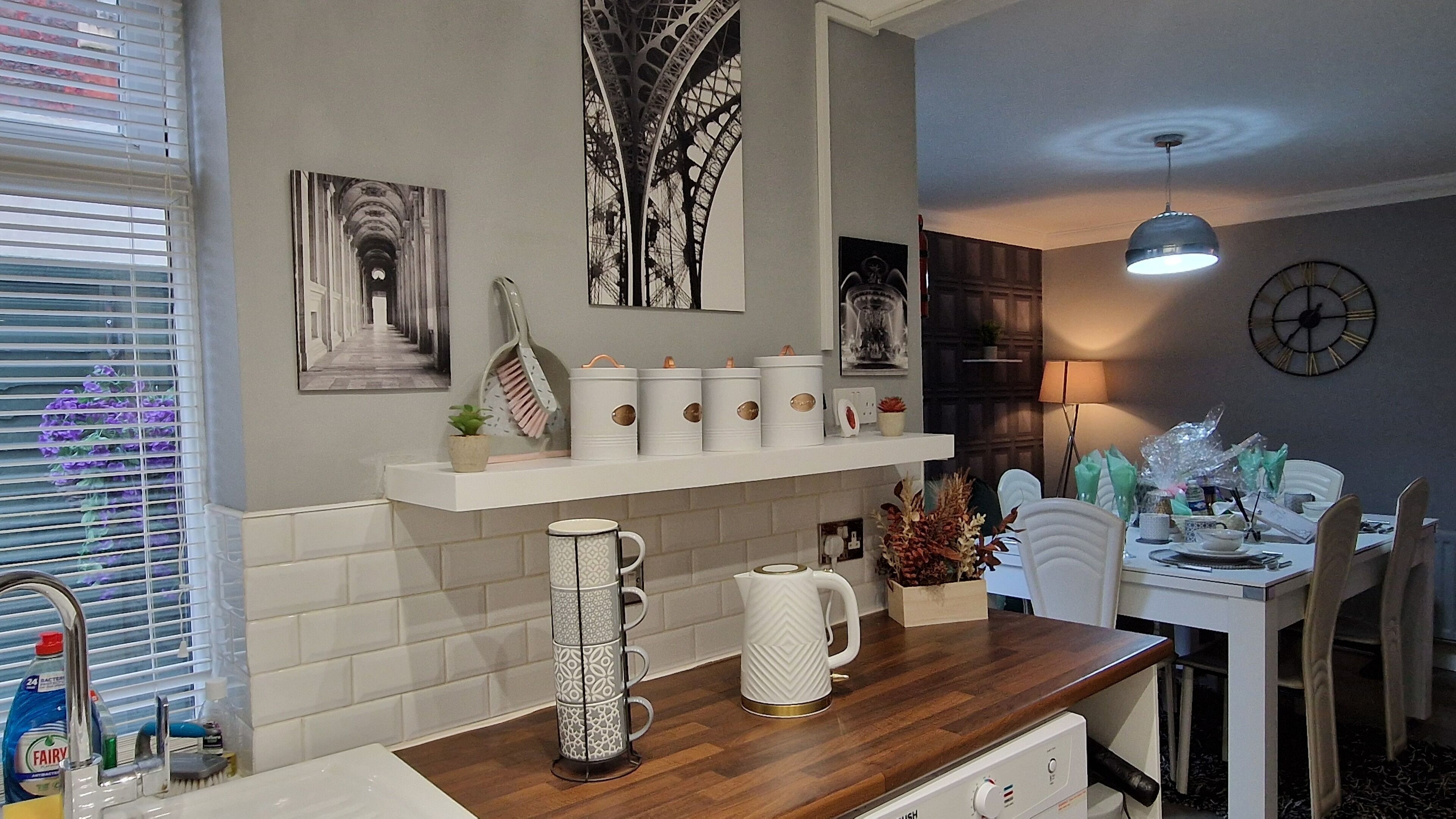 A modern kitchen with a wooden countertop, a coffee maker, and a decorative mirror.