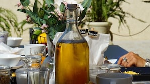 A table set with croissants, a bottle of olive oil, and various condiments, with a view of palm trees and a clear sky in the background. - Appartement 2 Chambres (Saint-Florent)