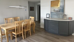 Un comedor con una mesa y sillas de madera, una isla de cocina gris con armarios, y un cuadro en la pared.