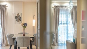 Un coin repas comprenant une table, des chaises, un vase avec des fleurs, une lampe et des rideaux.