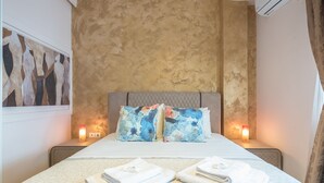 Un lit bien fait, avec des oreillers, deux lampes de chevet et des serviettes pliées posées sur une couvre-lit à motifs.