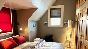 A bedroom with a bed, a window with a view, a bedside table, and a wardrobe. - Large Luxury Downtown "Design Studio" One Bedroom Apartment (Findlay)