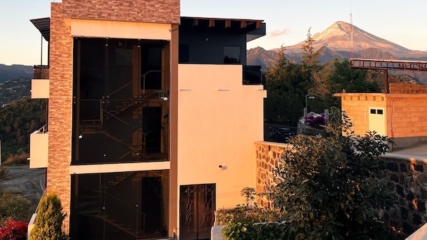 A modern two-story building with a glass entrance and a stone wall. - Xantico Palace (Ocuituco)