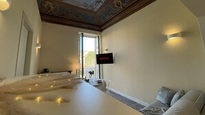 A hotel room with a bed, a TV mounted on the wall, a window, and a ceiling with decorative patterns. - [villa Migliorini] Lusso & Comfort in Finalborgo (Finale Ligure)