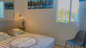 Una camera da letto con un letto, una sedia, un comodino, una lampada a parete e due quadri.