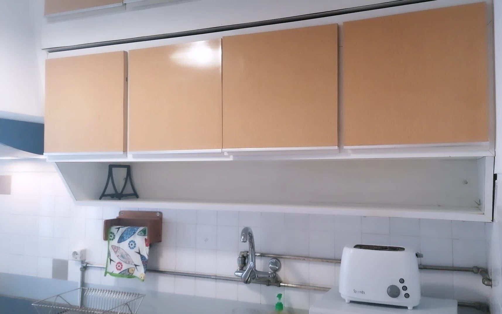 Una cocina con armarios color crema, encimera blanca, un tostador y un tendedero con un paño de cocina.