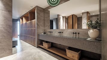 Bathroom features a large mirror, granite countertop with three sinks, and wooden cabinets.