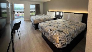 A hotel room with two beds, a desk, a chair, and a balcony with a view. - Studio 6 Conroe, TX (Conroe)