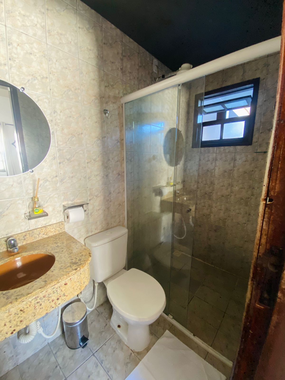 A bathroom with a marble sink, toilet, and glass-enclosed shower.