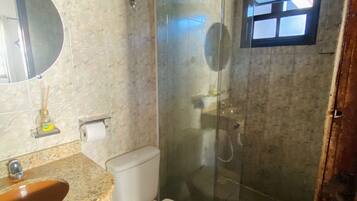 A bathroom with a marble sink, toilet, and glass-enclosed shower.