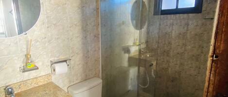 A bathroom with a marble sink, toilet, and glass-enclosed shower.