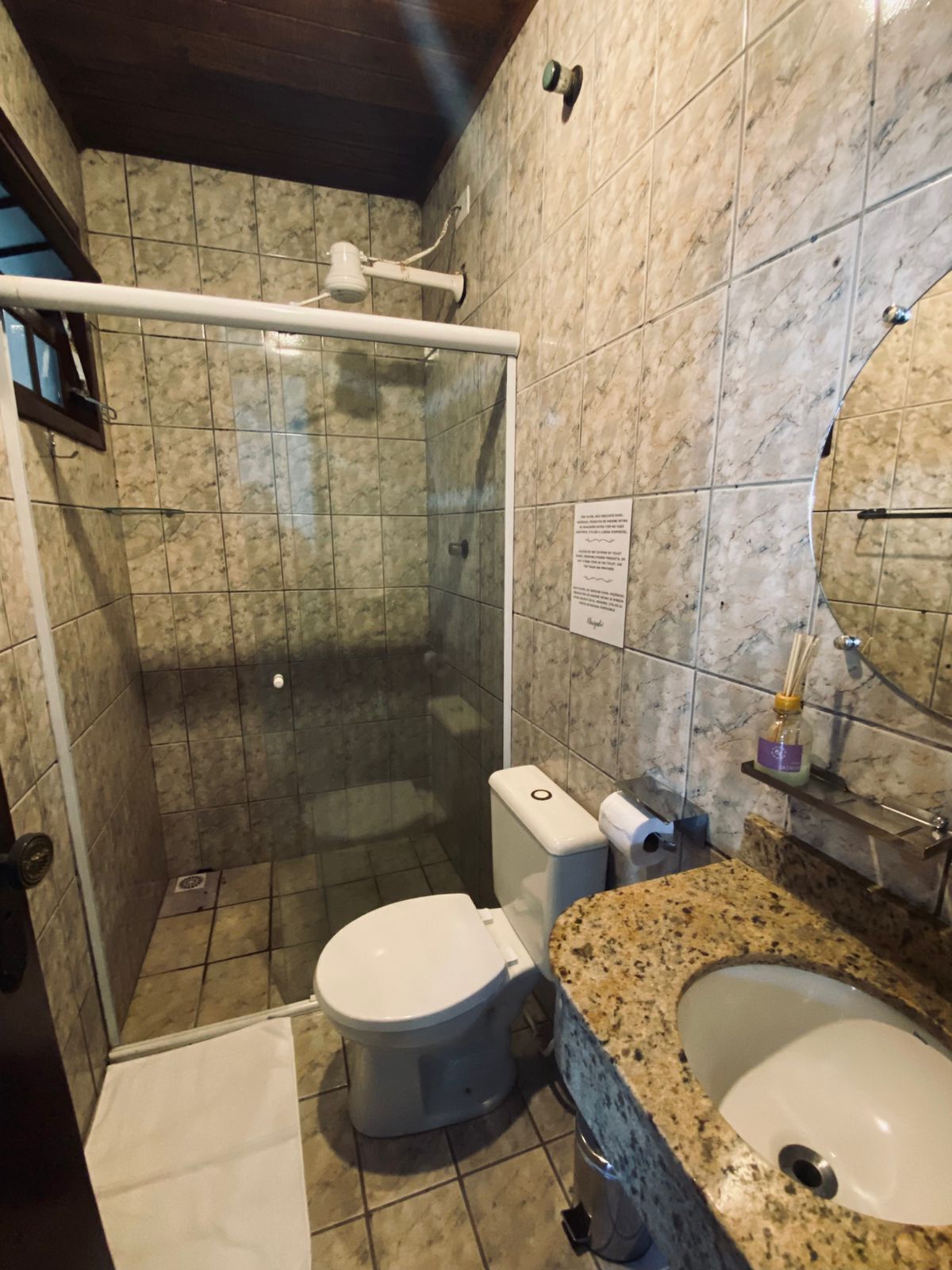 Un baño con ducha, inodoro, lavamanos y azulejos de mármol.