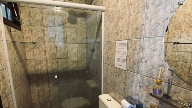 A bathroom with a shower, toilet, sink, and marble tiles.