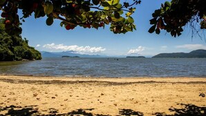 Una playa con agua cristalina, islas a lo lejos y un área boscosa.