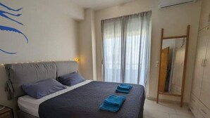 A bedroom with a bed, a nightstand, a mirror, and a window with curtains. - 5th-Floor Cozy Sea View, 2-Min Beach Walk (Chania)