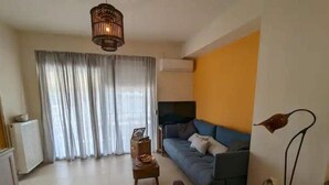 A living room with a sofa, a coffee table, a lamp, and a radiator. - 5th-Floor Cozy Sea View, 2-Min Beach Walk (Chania)