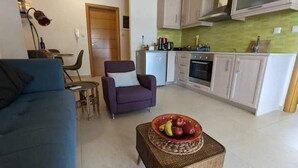 A living room with a sofa, armchair, and a small table with a fruit bowl. - 5th-Floor Cozy Sea View, 2-Min Beach Walk (Chania)