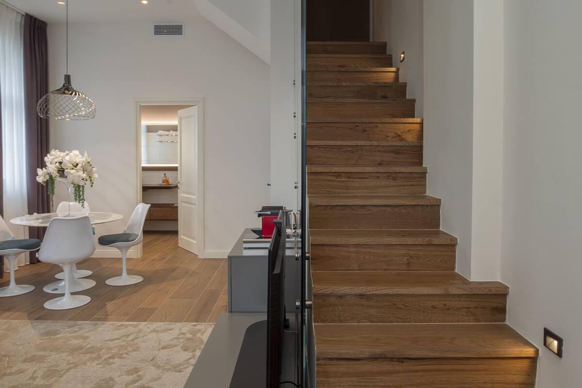 Una sala de estar moderna con comedor, una escalera y una cocina al fondo.