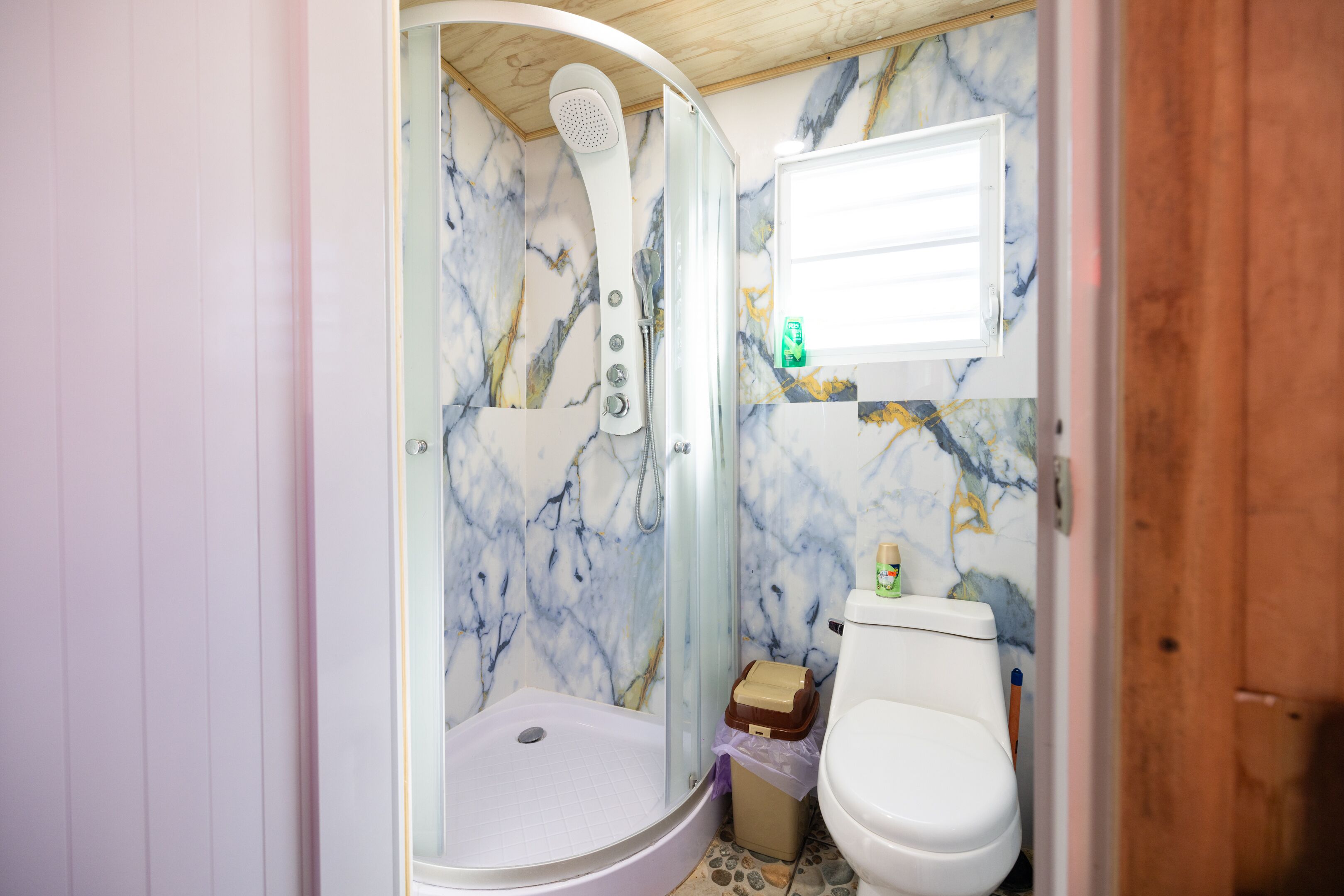 Et badeværelse med bruser, toilet og væg i marmor.