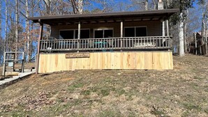 Uma cabana com um deck de madeira e uma placa com a inscrição 'The Cool Country Cabin'.