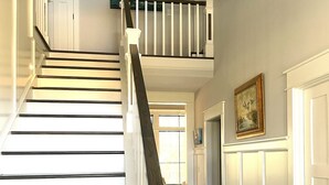 A staircase with white railings and dark wooden steps leading to an upper landing. - Custom 4-bedroom home, boat slip, fenced backyard, pool & paved bike path. (Cape Charles)