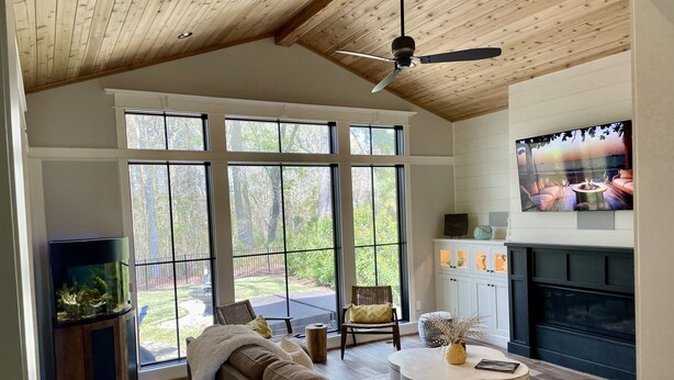 A spacious living room with a large window, a fireplace, a television, and a cozy seating area. - Custom 4-bedroom home, boat slip, fenced backyard, pool & paved bike path. (Cape Charles)