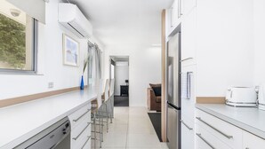 Una cucina moderna con mobili bianchi, elettrodomestici in acciaio inossidabile e vista sull'area pranzo.