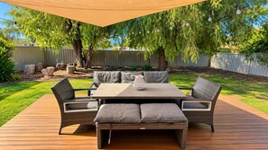 An outdoor patio with a table and chairs, surrounded by a wooden deck.