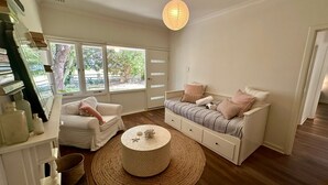 Una habitación acogedora con un sofá blanco, una mesita redonda y una ventana con vistas a zonas verdes.