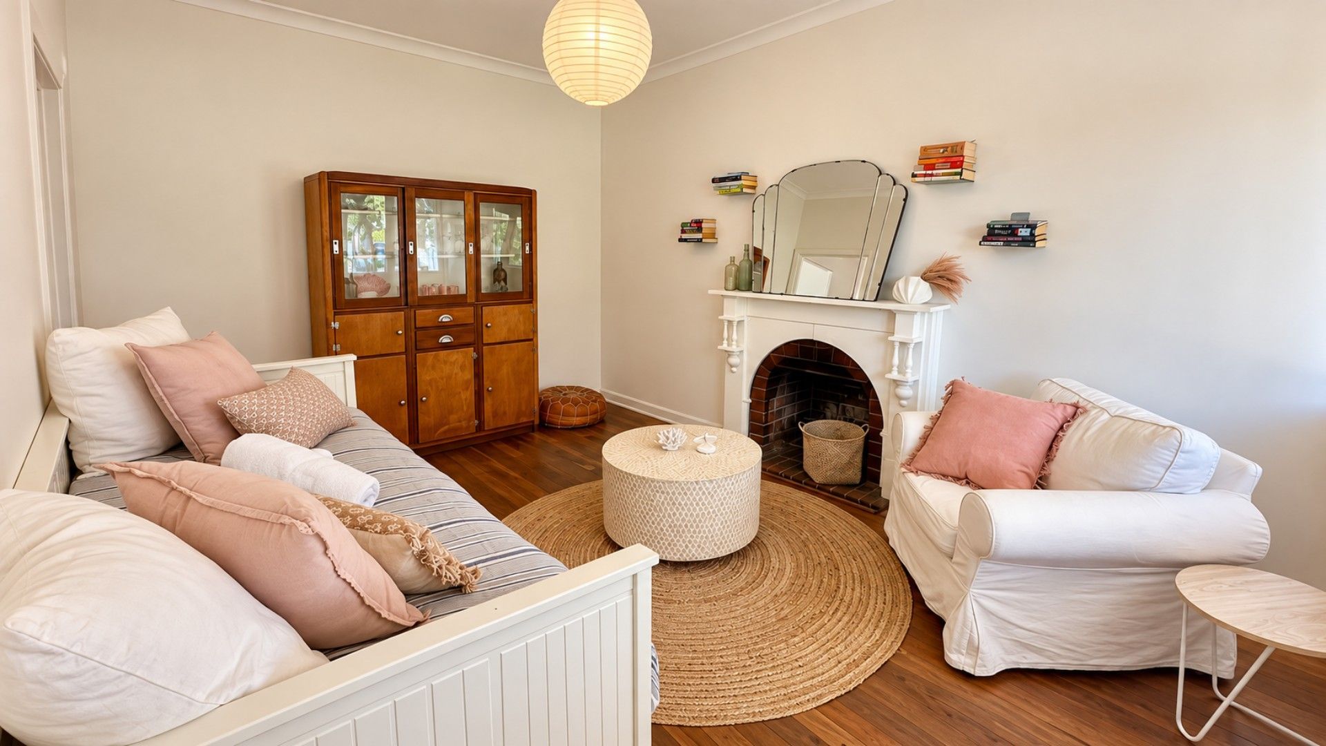 A living room with a white sofa, a wooden cabinet, a fireplace, and a round rug.