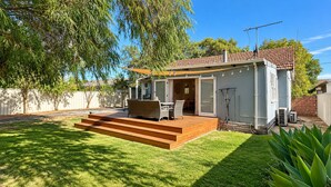 A house with a deck, outdoor seating, and a covered patio area.