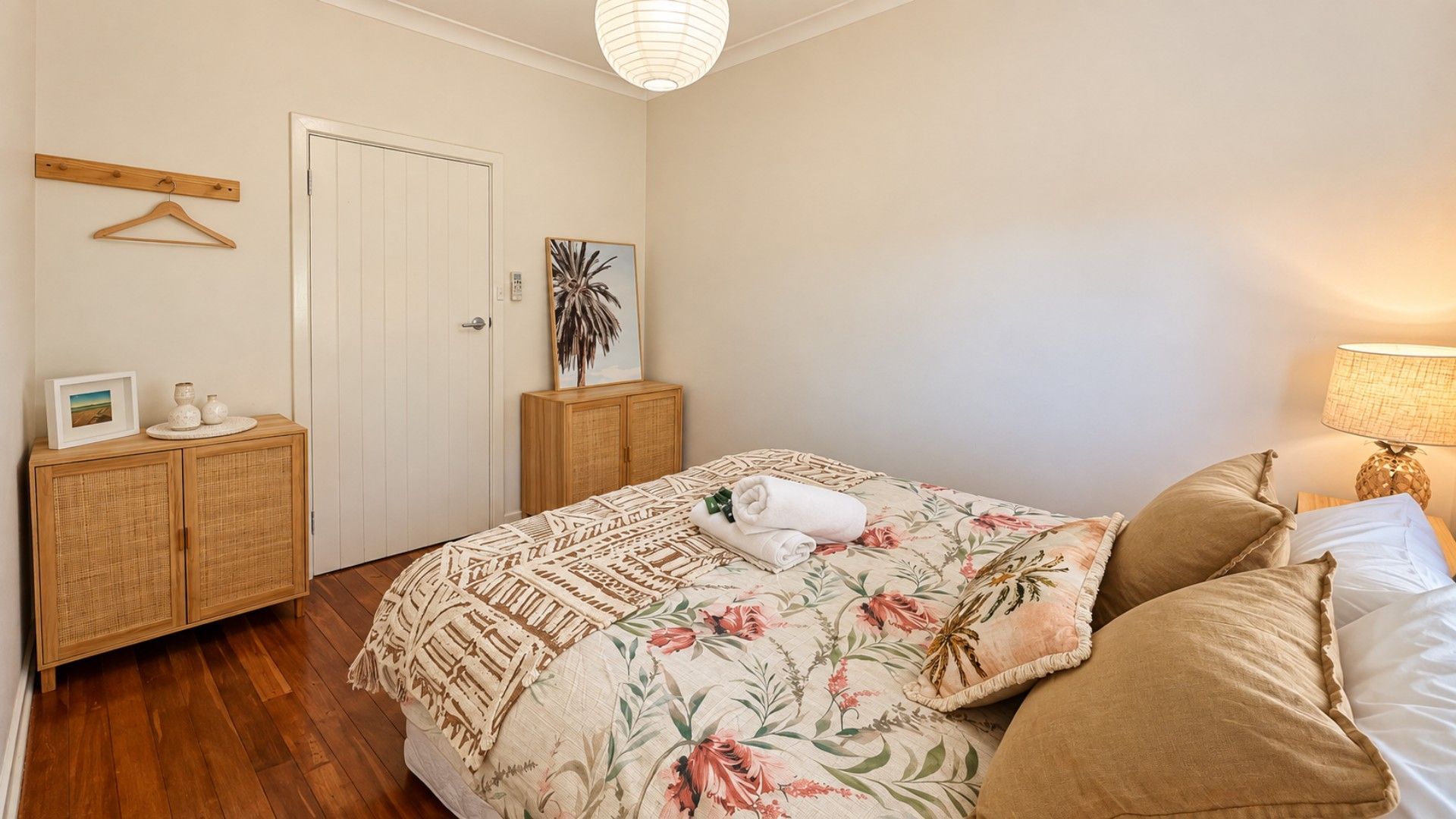 A bedroom with a bed, a wooden wardrobe, a door, and a wall-mounted shelf.