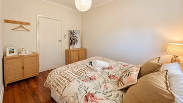 A bedroom with a bed, a wooden wardrobe, a door, and a wall-mounted shelf.