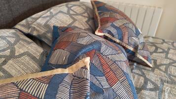 A bed with patterned pillows and a grey headboard.