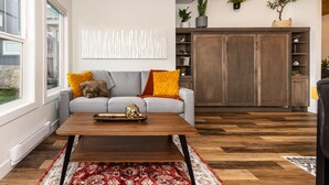 A modern living room with a grey sofa, a wooden coffee table, and a red patterned rug. - New Garden Studio I ProClean I Skylight I Rain Shower I Nespresso I Free Parking (Colwood)