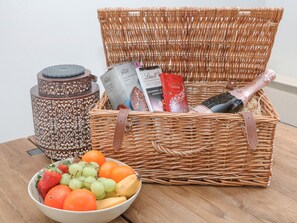 A wicker basket containing a bottle of Lindor, a box of Lindt chocolate, a box of Lindt cookies, and a book titled 'Excellenz'. - Sylvannah (Buxton)