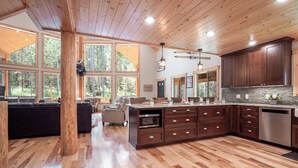 A spacious kitchen with wooden floors, large windows, and a central island. - Hot Tub, Firepit, Large Deck, Game Room, Secluded Mtn Views, 20 min to Park | Yellowstone Escape (Island Park)